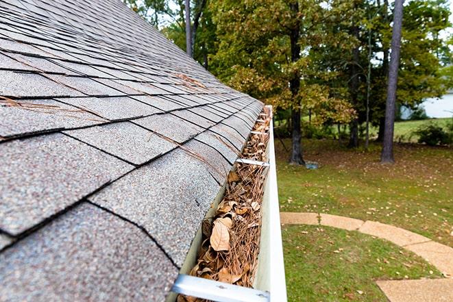 a professional using a pressure washer to clean gutters